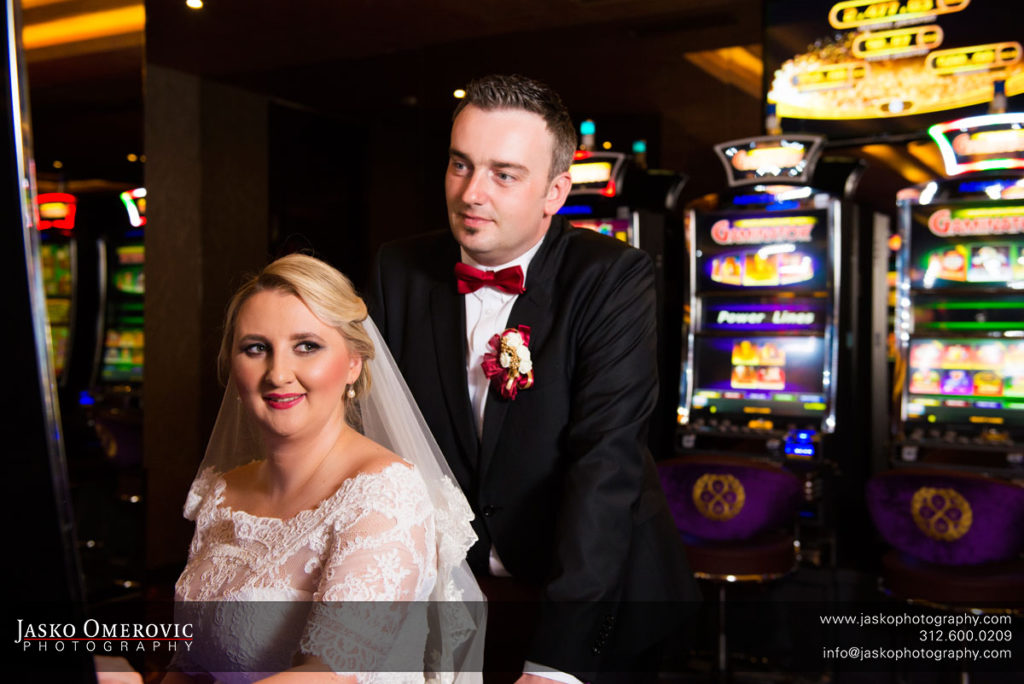 Bride and groom in casino surounded with slot machines.
