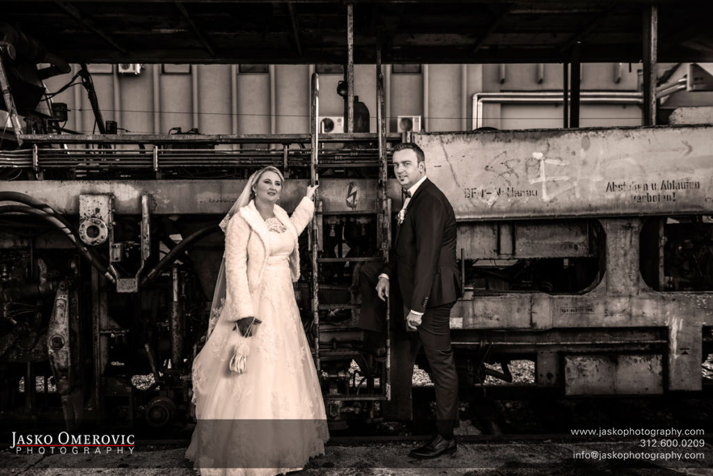 Bride and groom in front of the locomotive at the train station in sepia tone