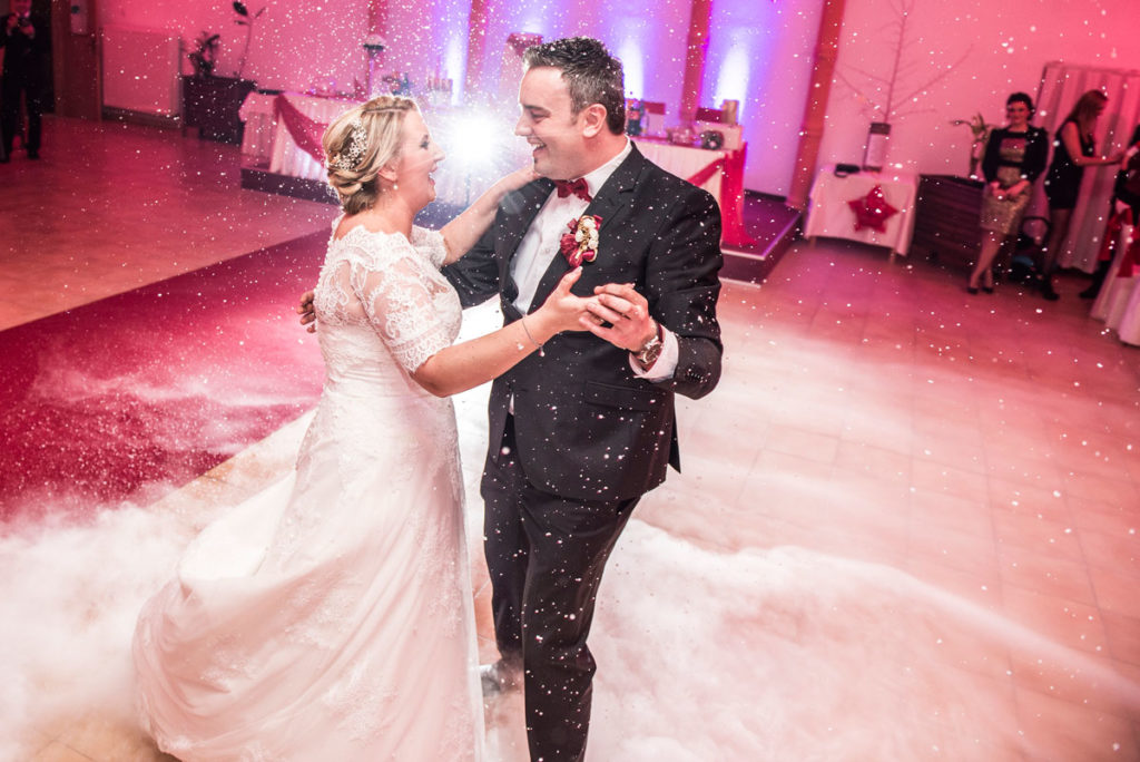 Bride and groom dancing while snowing, back light with a star light.