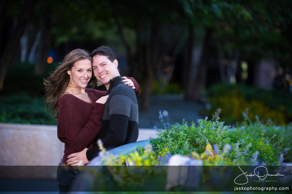 Engaged Couple Hugging surrounded with greenery