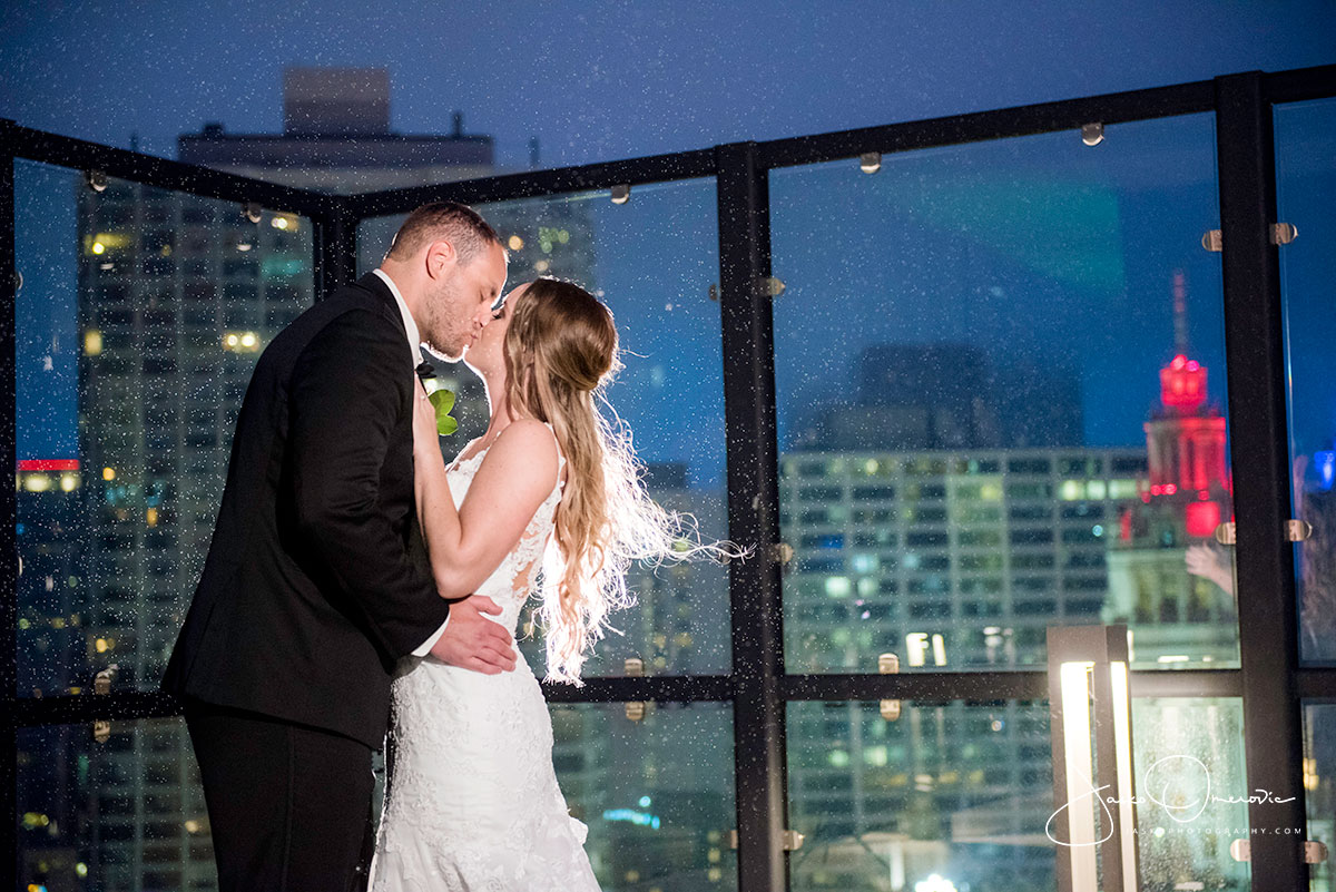 bride and groom kissing in the rain on the rooftop