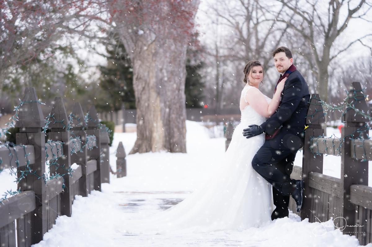 bride and groom leaning on the bridge for a winter photo wedding