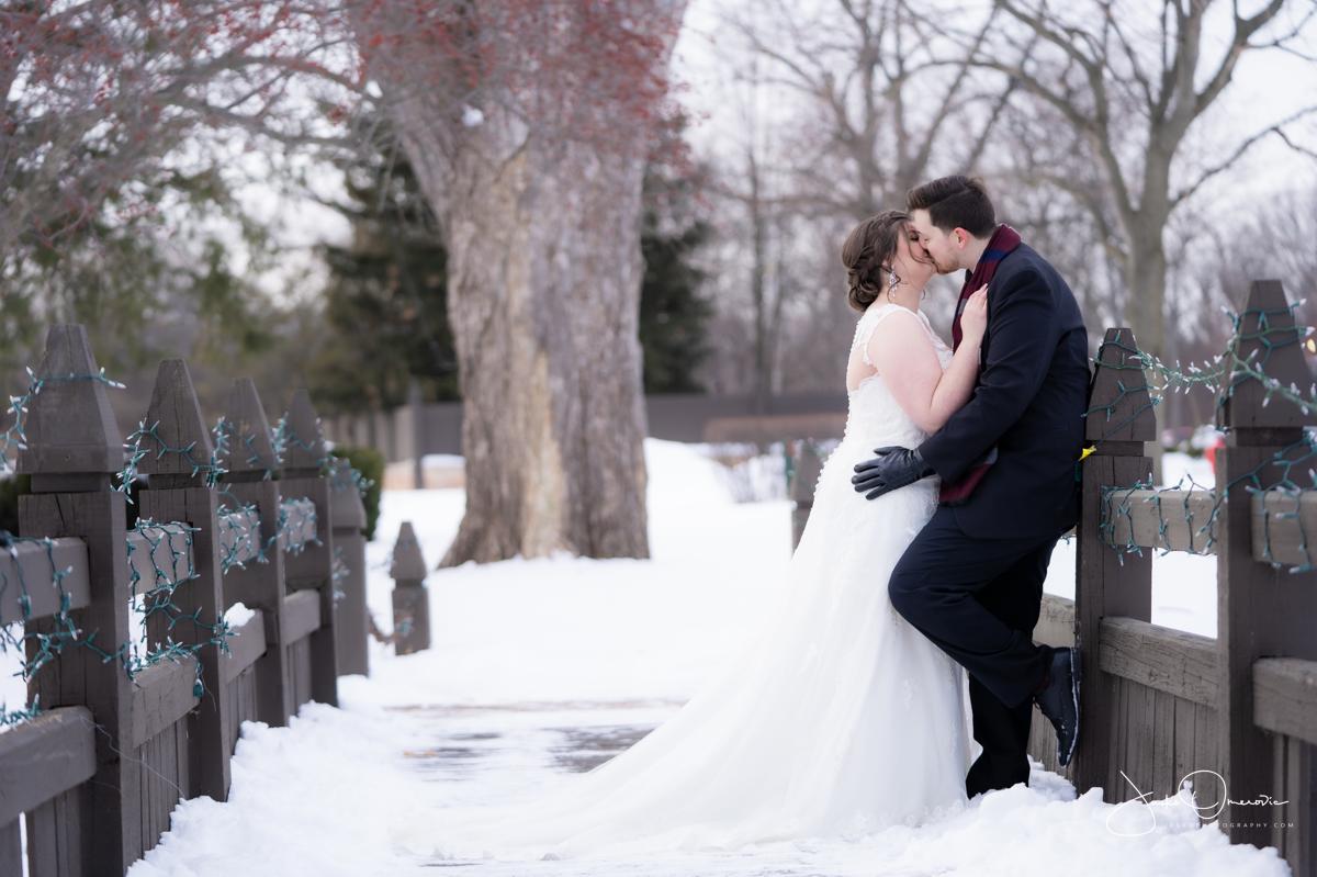 bride and groom kissing on the bridge surrounded by snow