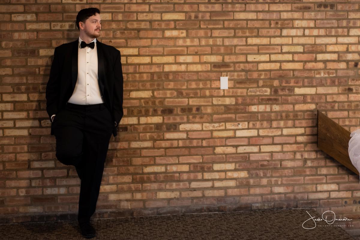 groom portrait agains brick wall at mission hills wedding in northbrook