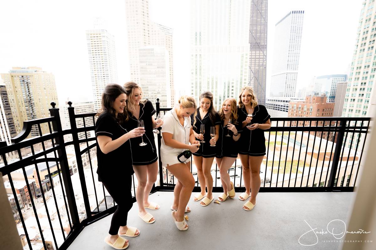 Champaign opening bride and bridesmaids on the balcony