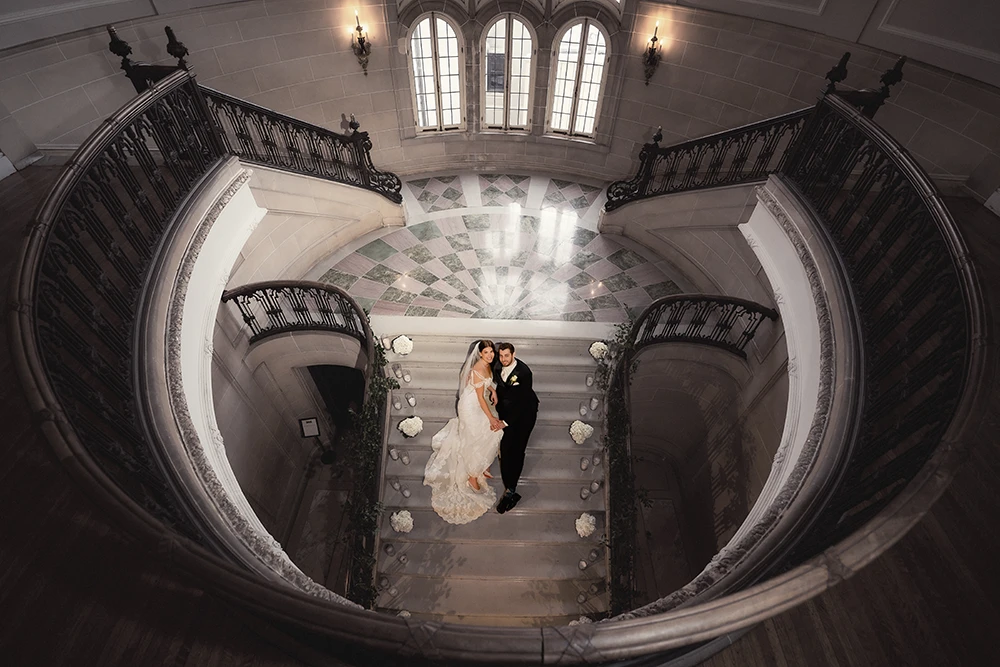 couple in the middle of the circular staircase looking up at the camera
