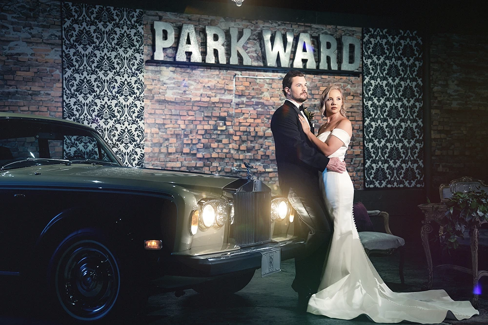dramatic wedding couple portrait leaning on a vintage rolls royce