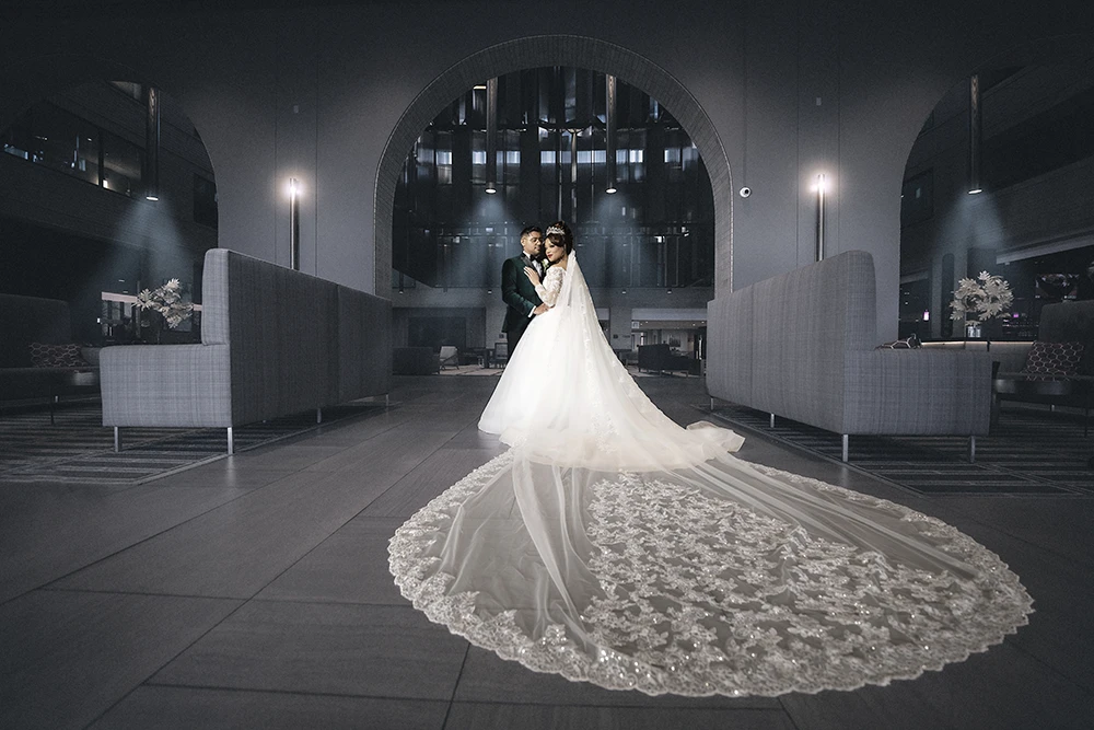 cinematic portrait of a couple at their wedding with brides long veil perfectly spread over the floor
