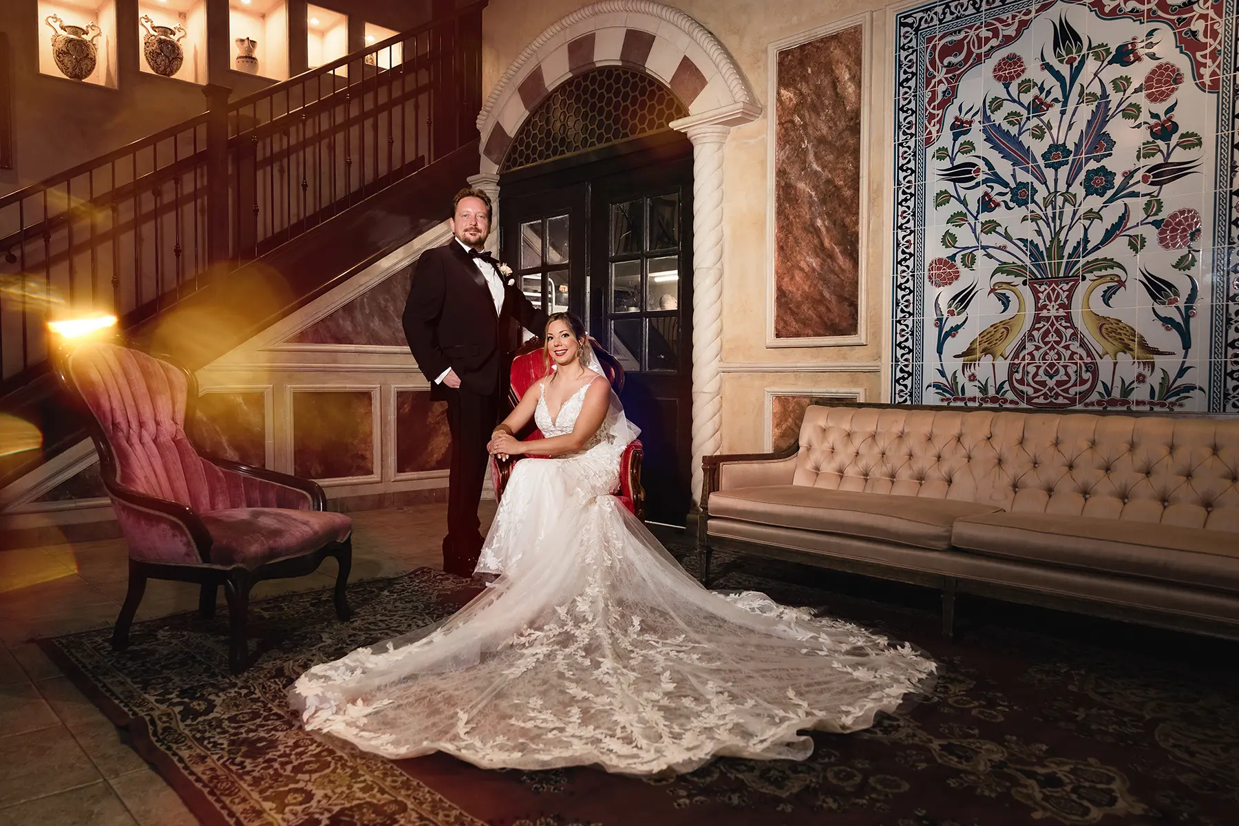 Bride and groom photographed inside Galleria Marchetti during their wedding, with the bride seated and the groom standing beside her in an elegant interior setting