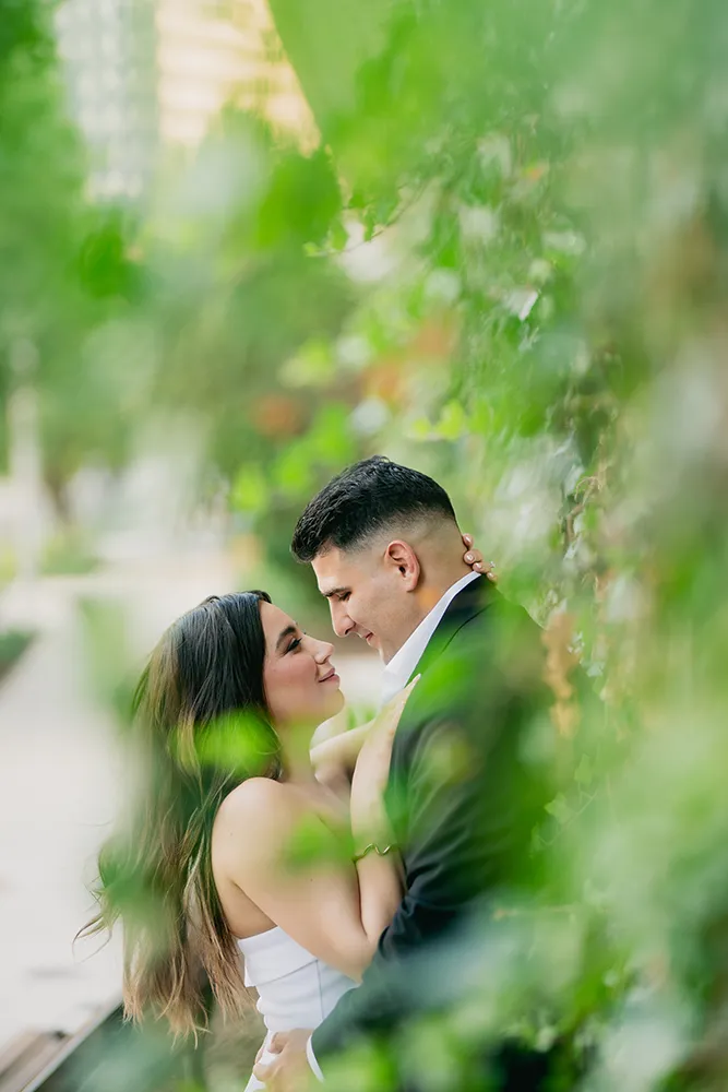 Romantic Chicago engagement portrait of a couple standing close in greenery
